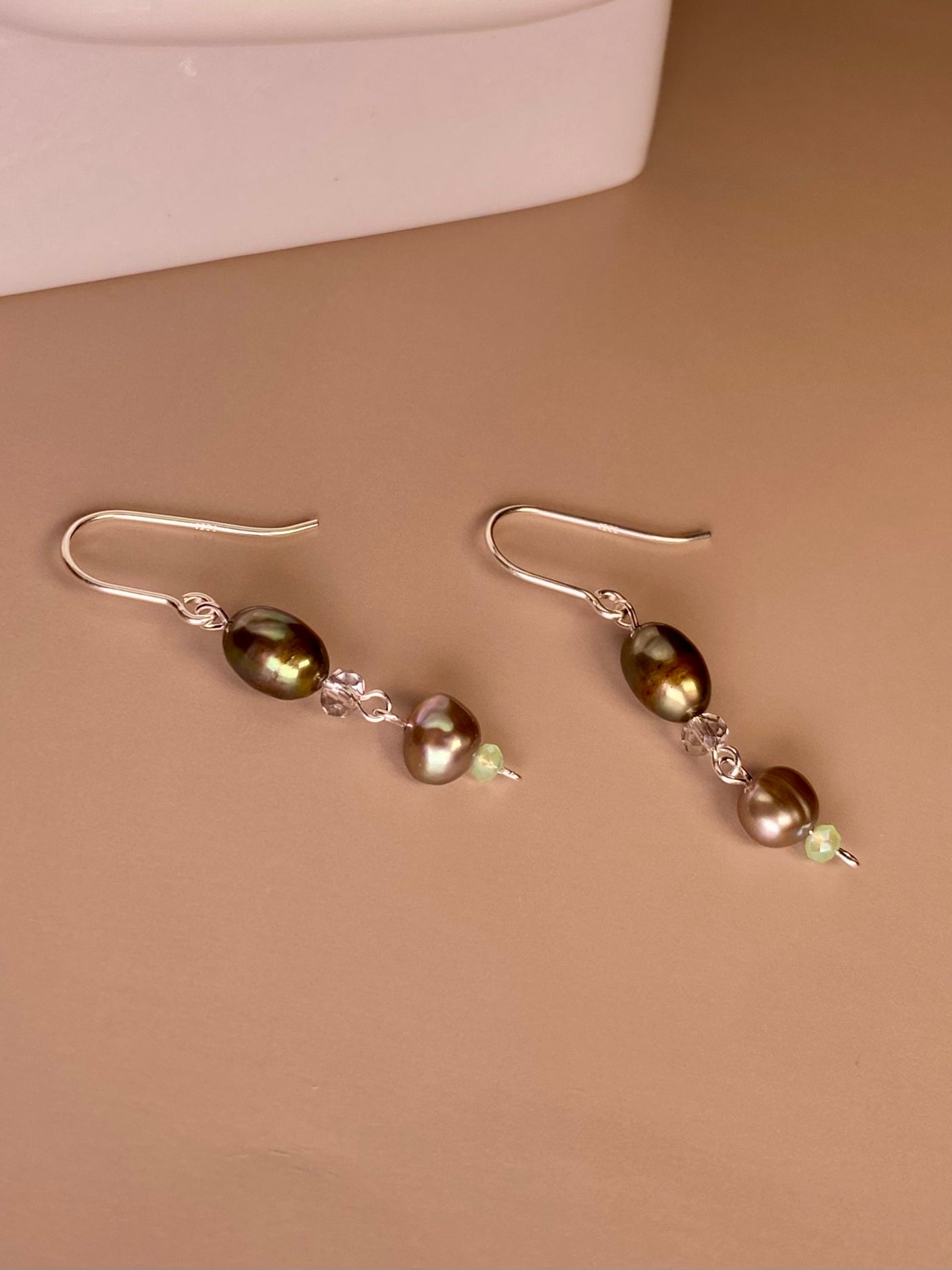Erin Pearl Dangle Earrings featuring 5mm-7mm brown and grey freshwater pearls and sparkling 2mm-3mm green and silver beads with elegant 925 sterling silver earring hooks and wire. Placed in the center, the earrings dazzle with their timeless beauty.