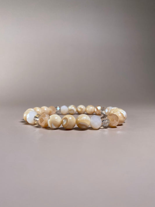 Stella 8mm Mother of Pearl Bracelet featuring three stunning 8mm mother of pearl beads and three variations of shiny cream opaque and translucent 6mm and 8mm beads, beautifully displayed in the center of the photo and sparkling.