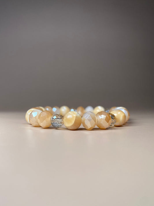 Stella 8mm Mother of Pearl Bracelet featuring three stunning 8mm mother of pearl beads and three variations of shiny cream opaque and translucent 6mm and 8mm beads, beautifully displayed in the center of the photo and sparkling.