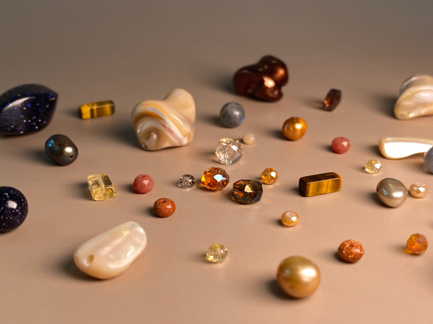 Photo depicting gemstones, glass beads, mother of pearl beads, tiger eye beads, citrine beads, moon stone beads and pearls used in jewelry making.